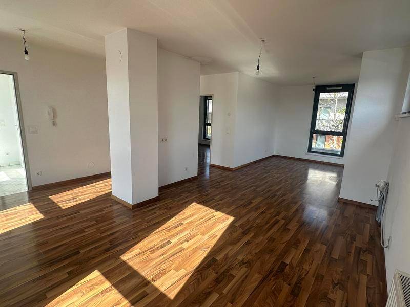 Geräumiger Wohnbereich mit Holzboden und Säule, der eine offene Gestaltung andeutet.