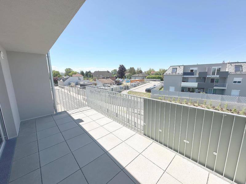 Heller Balkon mit moderner Brüstung und weitem Blick über die Nachbarschaft.