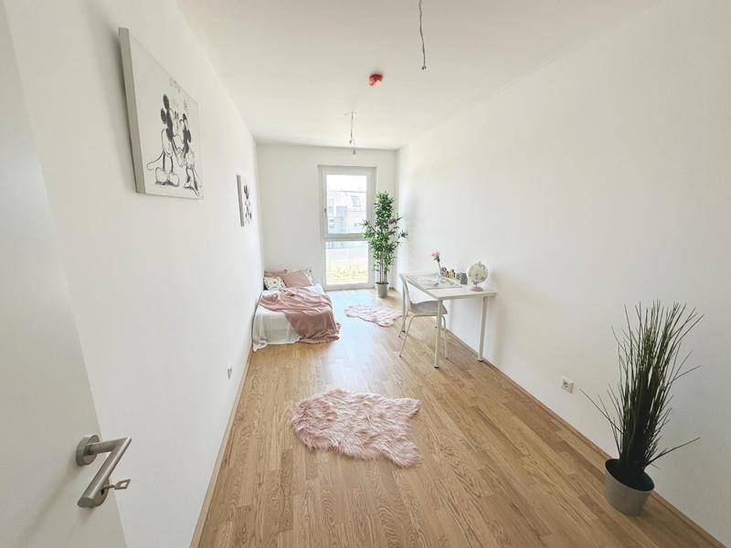 Gemütliches Kinderzimmer mit hellem Parkettboden, Schreibtisch und Fenster.