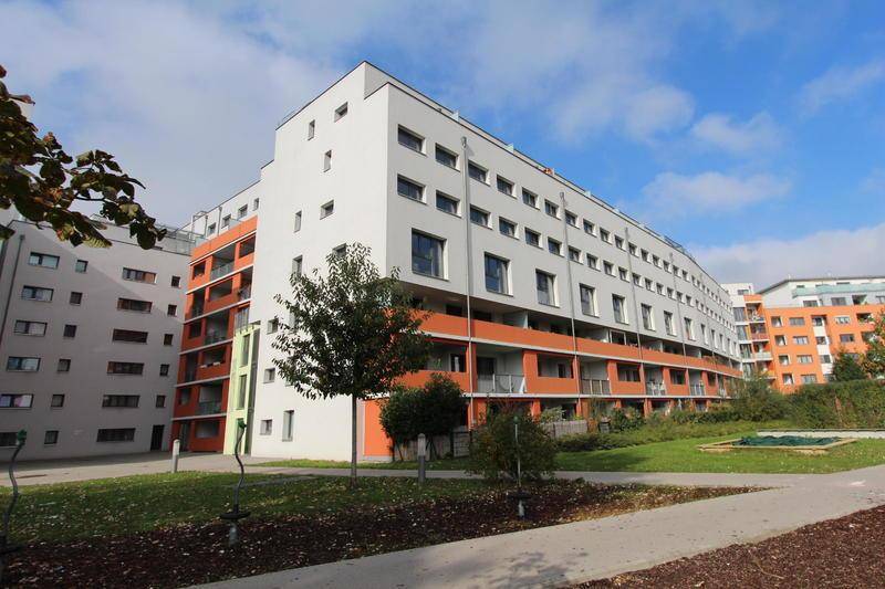 Attraktive Wohngebäude mit moderner Architektur und farbigen Akzenten in einer grünen Umgebung.