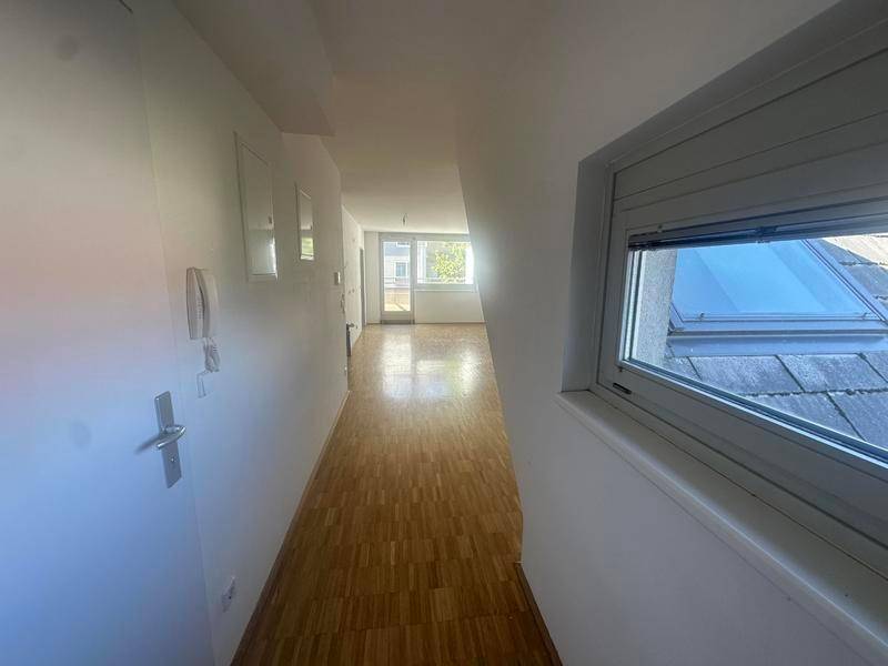 Langer Flur mit Parkettboden und einem Dachfenster, das für Helligkeit sorgt.