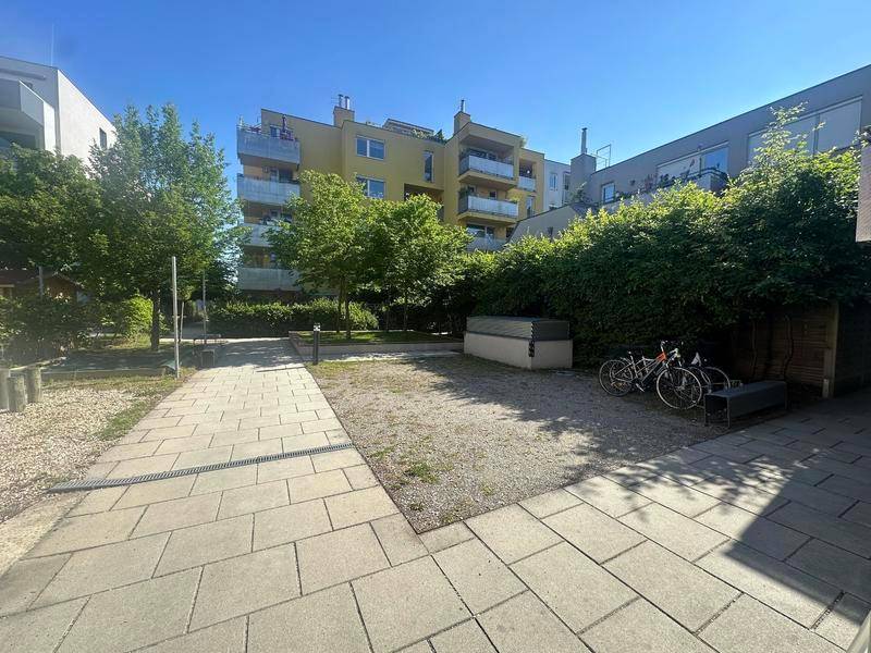Gemeinschaftlicher Außenbereich mit Kieswegen, Grünflächen und Fahrradabstellplätzen.
