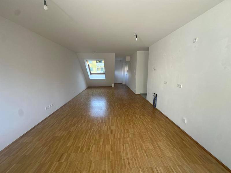 Heller Raum mit Parkettboden und Dachschräge, ausgestattet mit einem Dachfenster für natürliches Licht.