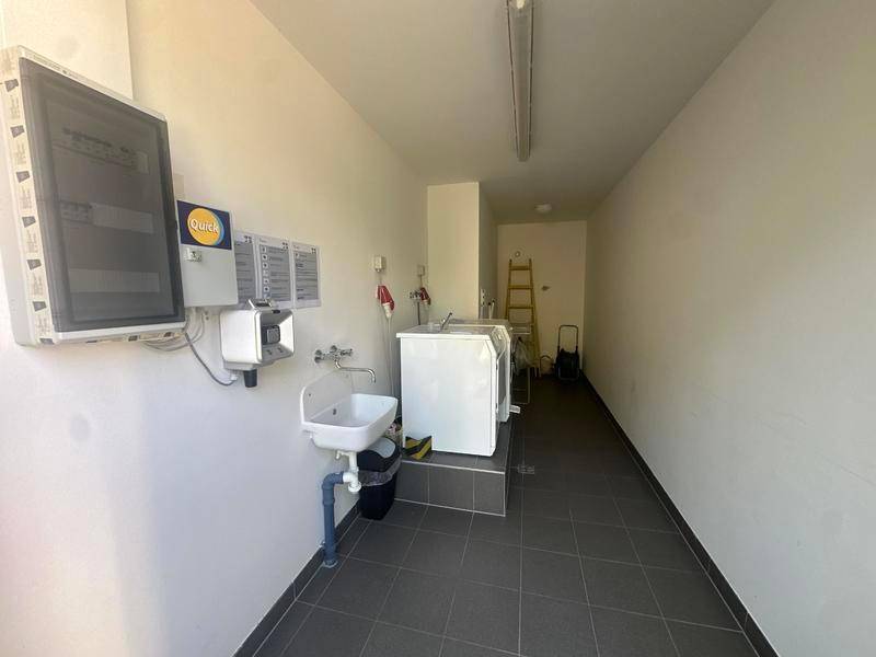 Funktionaler Hauswirtschaftsraum mit Waschbecken, Waschmaschine und elektrischen Schaltkästen.