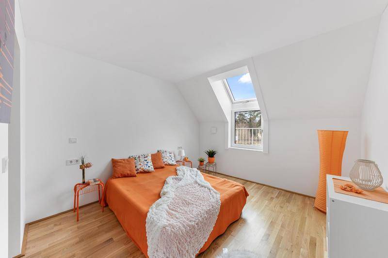 Gemütliches Schlafzimmer mit Dachschräge, Holzboden und einem Dachfenster mit Balkonzugang.