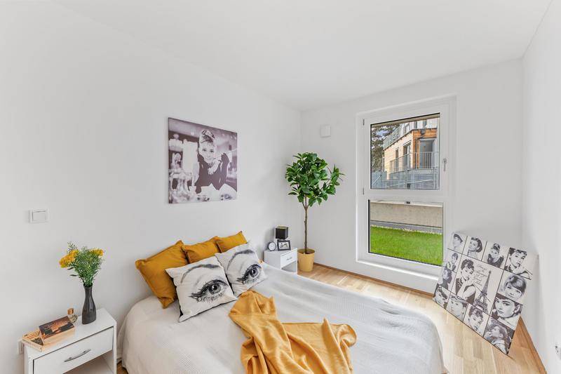 Helles Schlafzimmer mit Holzboden, großem Fenster und Blick auf eine grüne Rasenfläche.