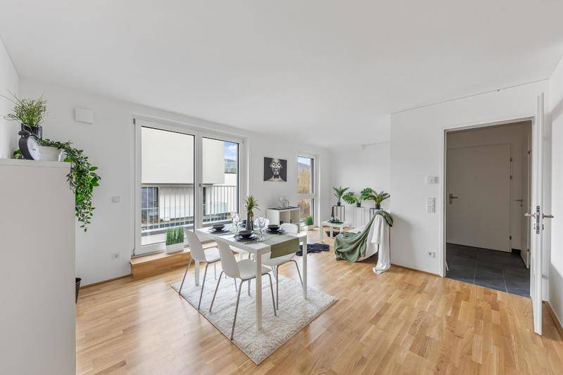 Heller Wohn-Essbereich mit Esstisch, Holzboden und großen Fenstern, teilweise mit französischem Balkon.