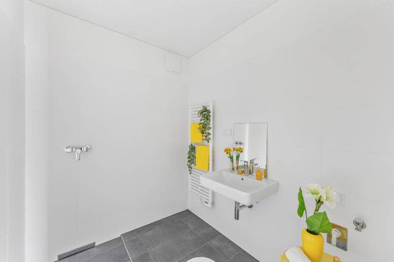 Modernes Badezimmer mit ebenerdiger Dusche, Einzelwaschbecken und beheiztem Handtuchhalter.