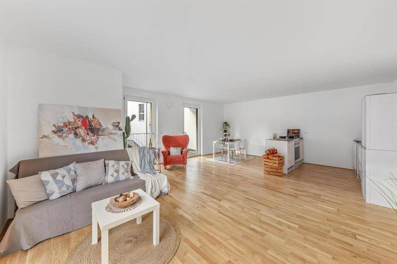 Großzügiger Wohn-Essbereich mit Sofa, Esstisch und integrierter Küchenzeile auf Holzboden.