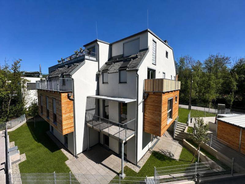 Moderne Wohnanlage mit weißer Fassade, Holzverkleidung und mehreren Balkonen und Terrassen.