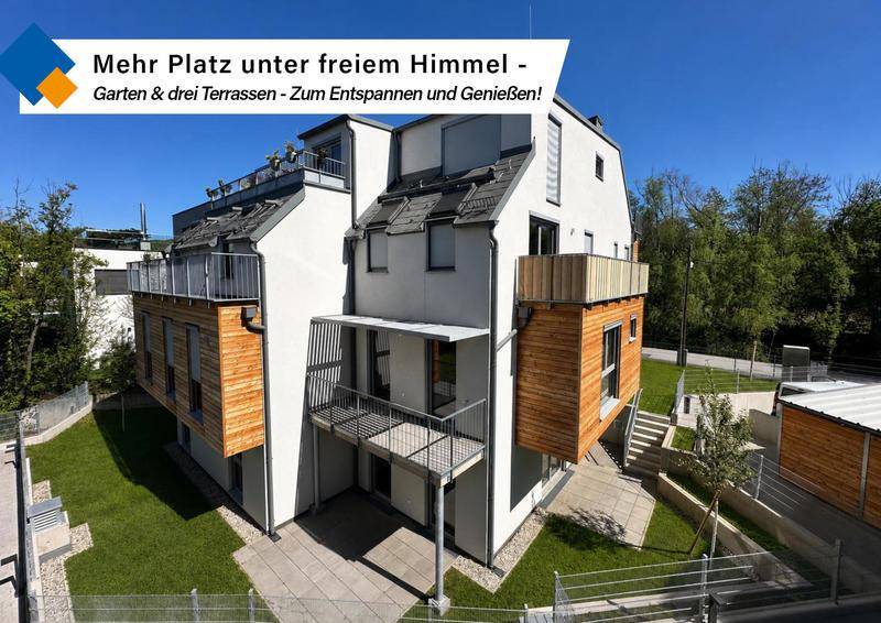 Modernes Mehrfamilienhaus mit mehreren Terrassen, Balkonen und einem gepflegten Gartenbereich.