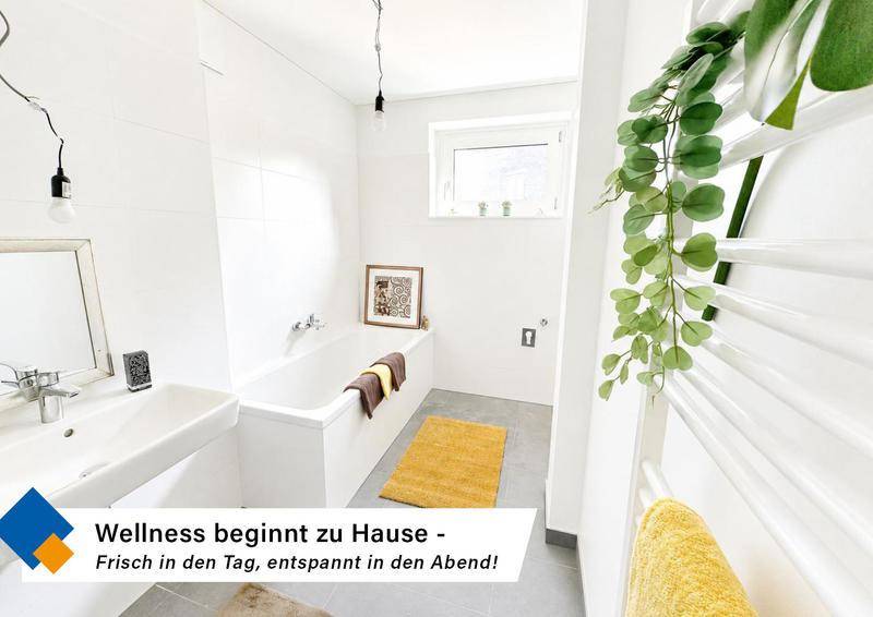 Modernes Badezimmer mit weißen Fliesen, Badewanne, Waschbecken und beheiztem Handtuchhalter.