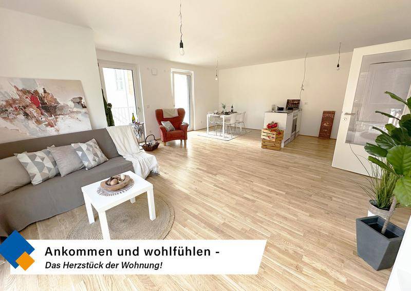 Offener Wohn- und Essbereich mit hellem Holzfußboden, gemütlichem Sofa und Zugang zum Balkon.