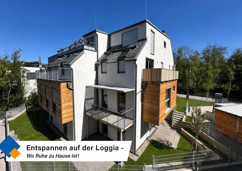 Rückansicht des modernen Gebäudes mit mehreren Loggien und Balkonen, umgeben von Grünflächen.