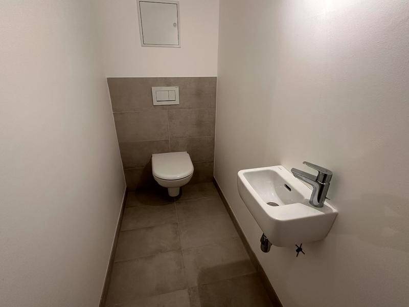 Kleines Gäste-WC mit wandhängender Toilette und modernem Waschbecken in minimalistischem Design.