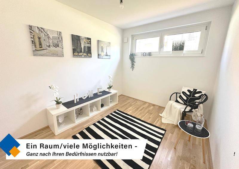 Vielseitiger Raum mit Holzboden, großem Fenster und moderner Dekoration, ideal als Schlaf- oder Arbeitszimmer.