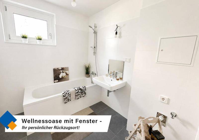 Modernes Badezimmer mit Badewanne, Fenster und weiß gefliesten Wänden für eine helle Atmosphäre.