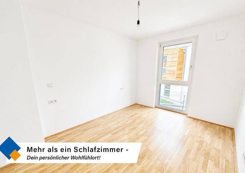 Helles Schlafzimmer mit Holzboden und großem Fenster, das viel Tageslicht hereinlässt.