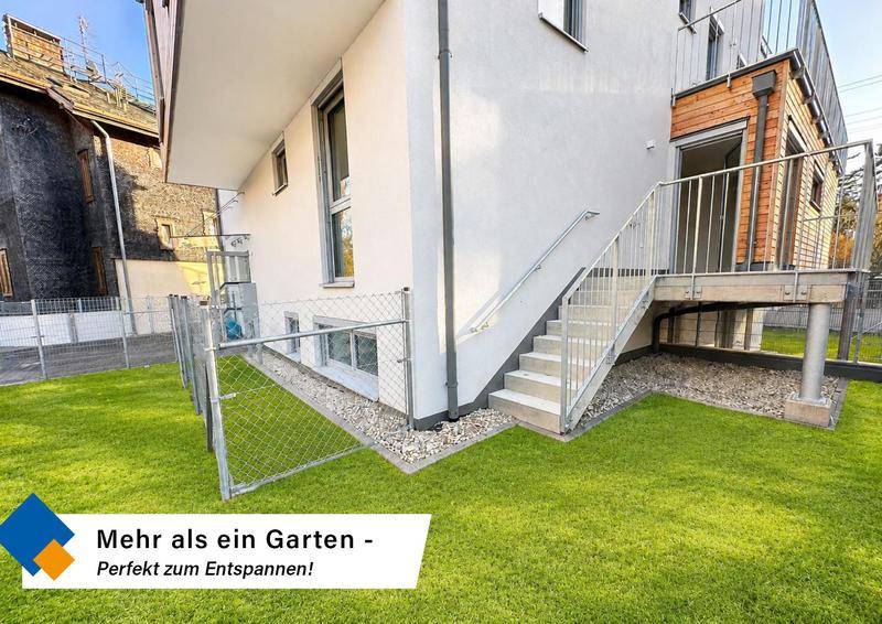 Gepflegte Rasenfläche neben dem Gebäude mit Außentreppe, ideal zum Entspannen im Freien.