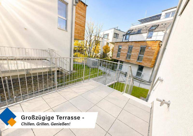 Großzügige, sonnige Terrasse mit Fliesenboden und Blick auf die umliegenden Gebäude.