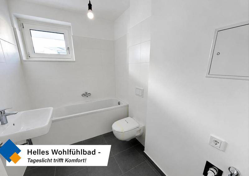 Helles Badezimmer mit Badewanne, WC, Waschbecken und einem Fenster für Tageslicht.