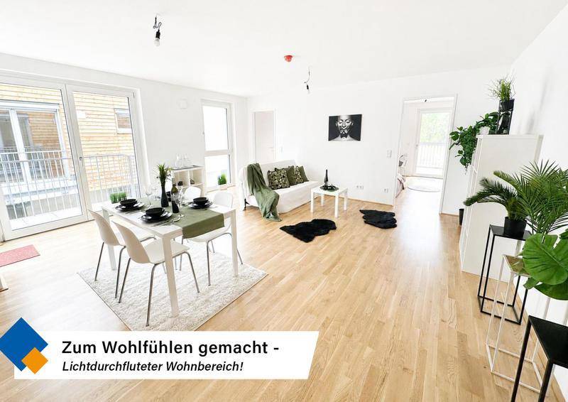 Lichtdurchfluteter Wohn-Essbereich mit Holzboden und Zugang zu einem Außenbereich.