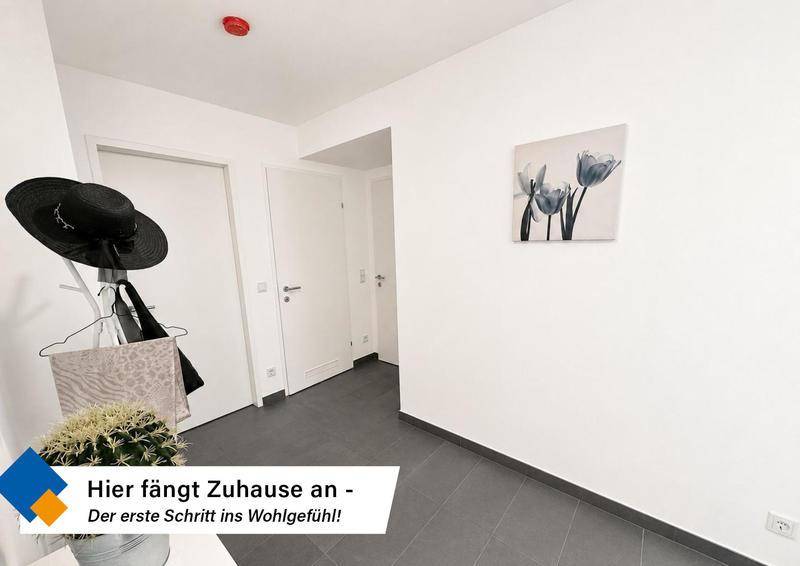 Heller Eingangsbereich mit dunklen Fliesen und Garderobe, einladend gestaltet.