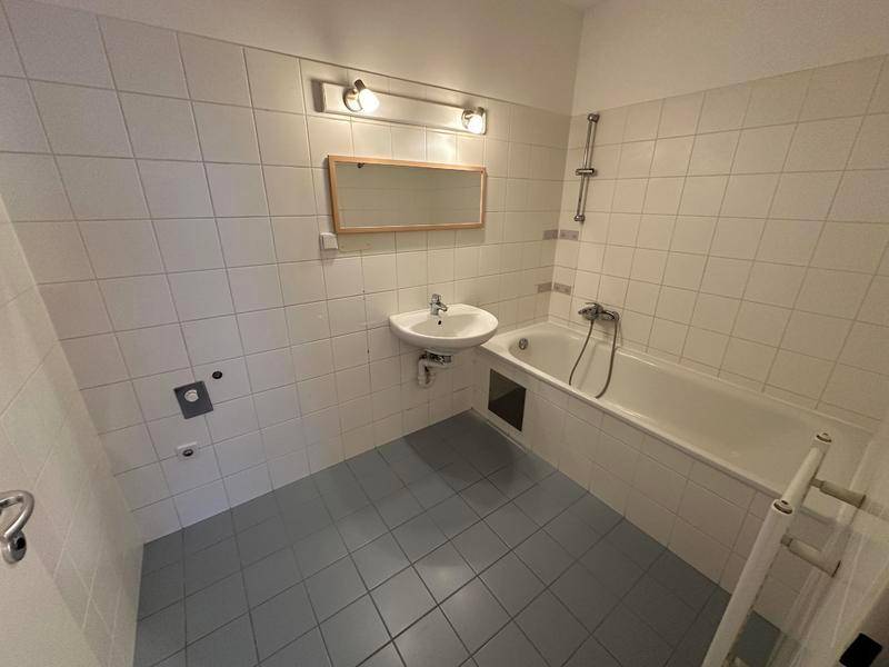 Funktionales Badezimmer mit Badewanne, Waschbecken und hellen Fliesen.