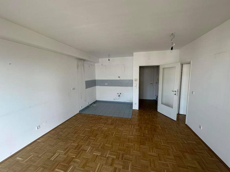 Offener Wohnbereich mit Parkettboden und gefliestem Bereich, ideal für eine Küche.