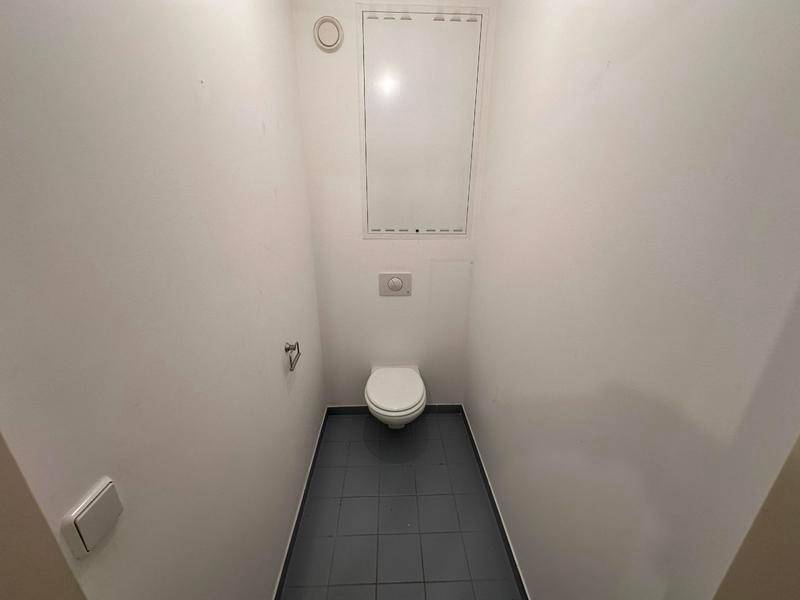 Separates WC mit Wand-WC und dunklen Bodenfliesen.