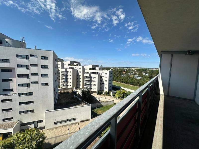 Sonniger Balkon mit Panoramablick auf die Wohngebäude und grüne Landschaft in der Ferne.