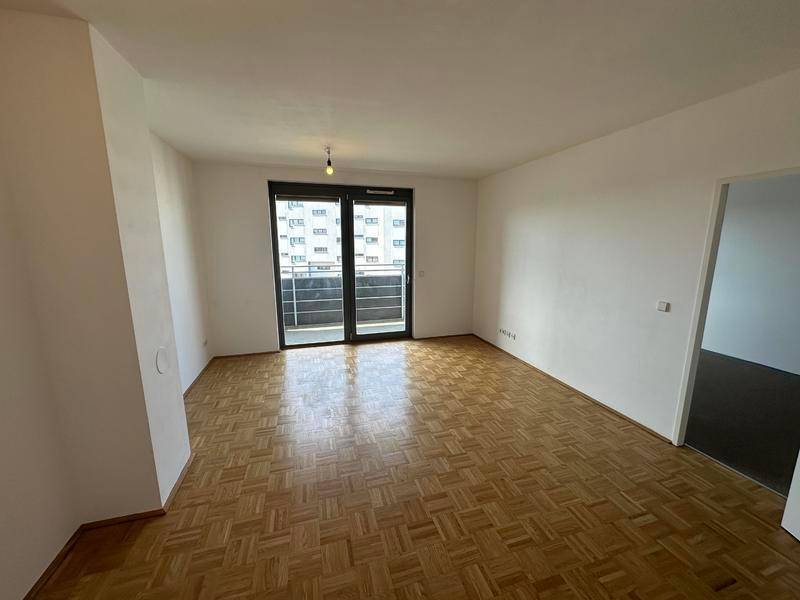 Geräumiges Wohnzimmer mit klassischem Parkettboden und viel Tageslicht.