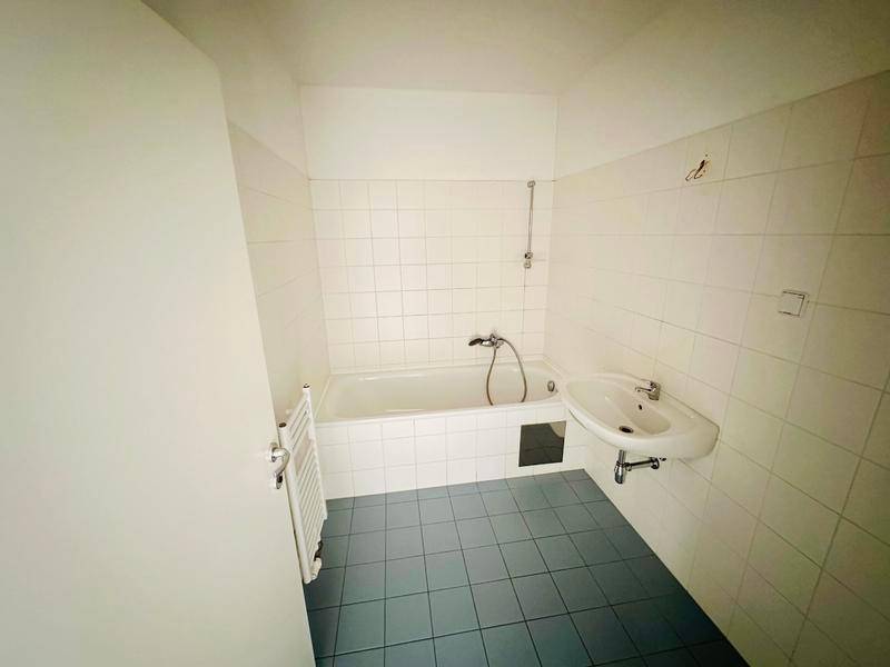 Badezimmer mit Badewanne, Waschbecken und weiß gefliesten Wänden.