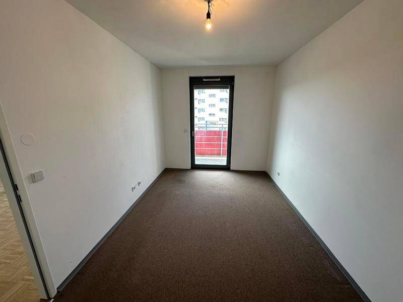 Schlafzimmer mit Teppichboden und Zugang zu einem kleinen Balkon.