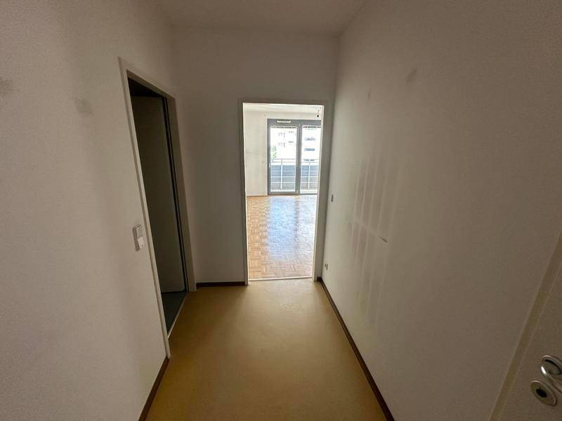 Schmaler Flur mit hellem Bodenbelag, der zu einem weiteren Wohnbereich führt.