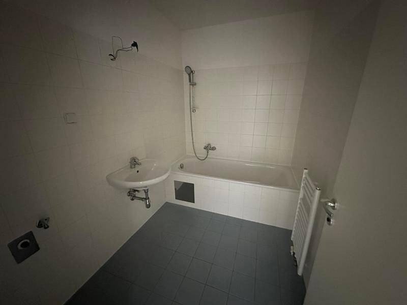 Funktionales Badezimmer mit Badewanne, Waschbecken und weißen Wandfliesen.