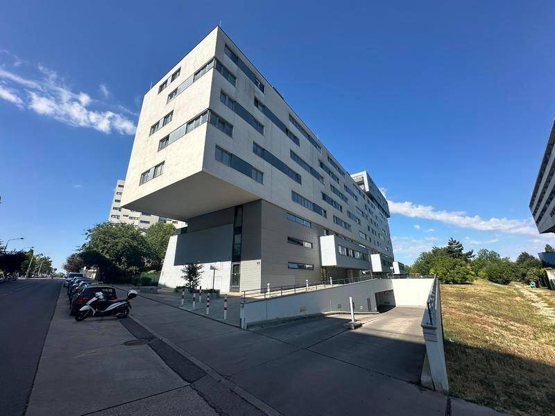 Ansicht der modernen Wohnanlage von der Straße mit Tiefgaragenzufahrt und gepflegter Umgebung.