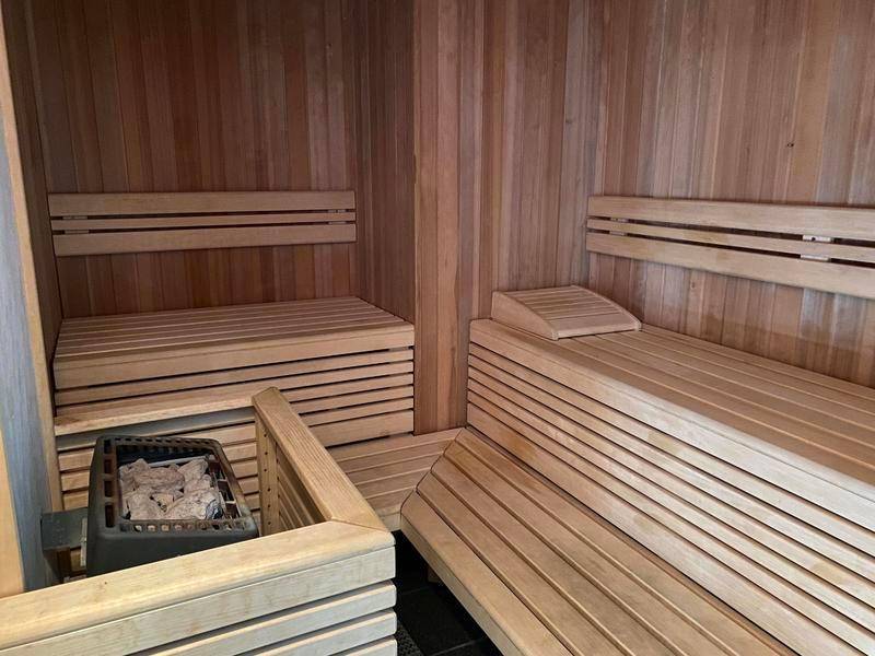 Holzvertäfelte Sauna mit Sitzbänken und Saunaofen für Entspannung.