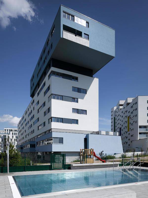 Modernes Wohngebäude mit Außenpool und Kinderspielplatz in der Anlage.