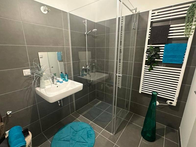 Modernes Badezimmer mit dunklen Fliesen, ebenerdiger Dusche und beheiztem Handtuchhalter.