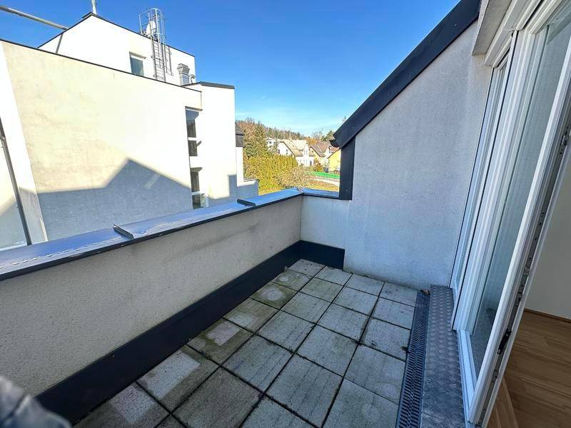 Kleiner Balkon mit Fliesenboden und Blick auf die umliegenden Gebäude und Grünflächen.