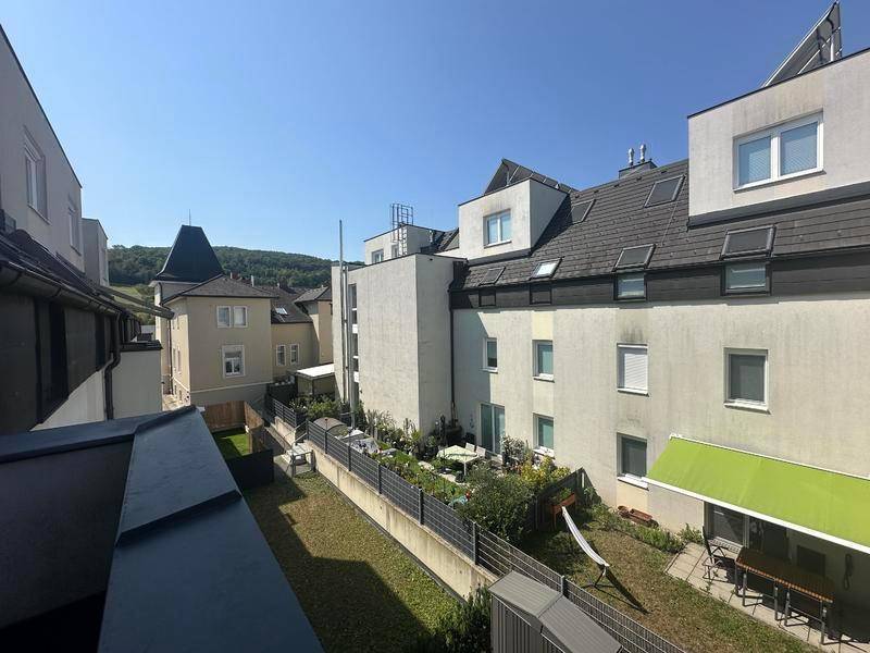 Blick auf die Rückseite eines Wohnkomplexes mit Gärten und angrenzenden Gebäuden.