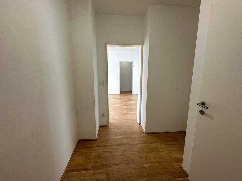 Schlichter Flur mit Holzparkettboden, der den Zugang zu weiteren Räumen ermöglicht.