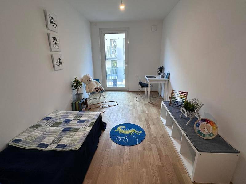 Helles Kinderzimmer mit Holzboden, Zugang zum Balkon und moderner Dekoration.
