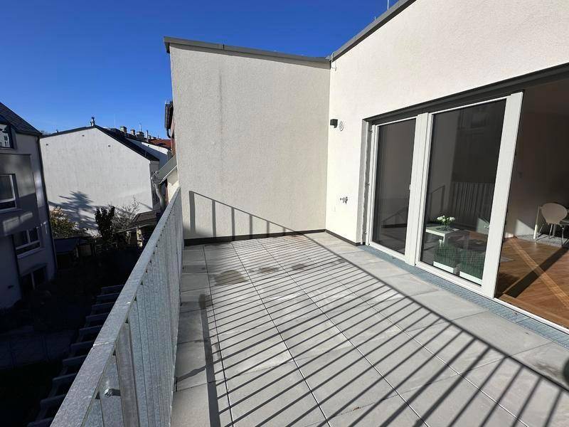 Sonniger Balkon mit Fliesenboden und Blick auf die umliegende Wohnbebauung.