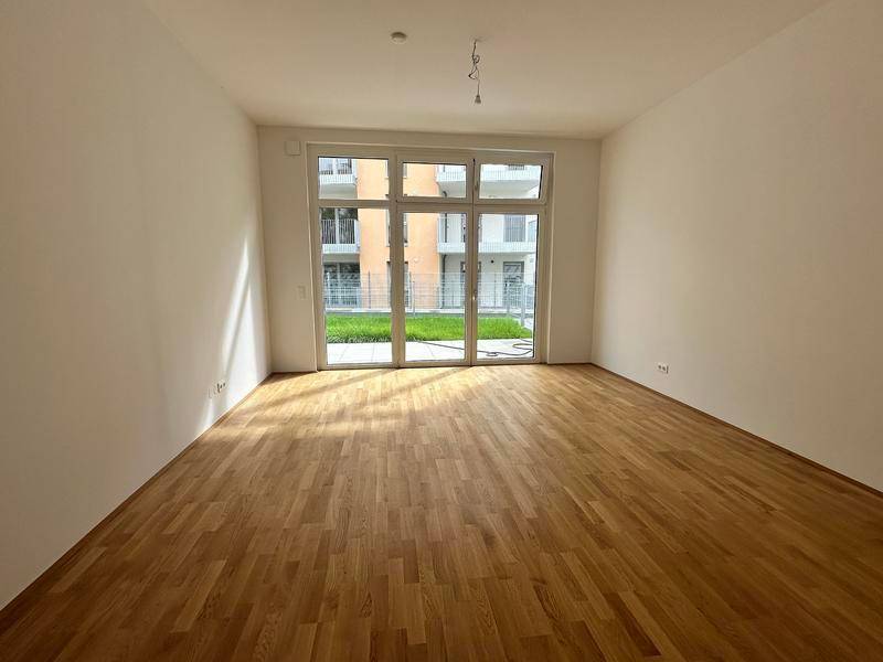 Lichtdurchfluteter Raum mit Holzboden und Zugang zu einer Terrasse, ideal für Wohnbereiche.