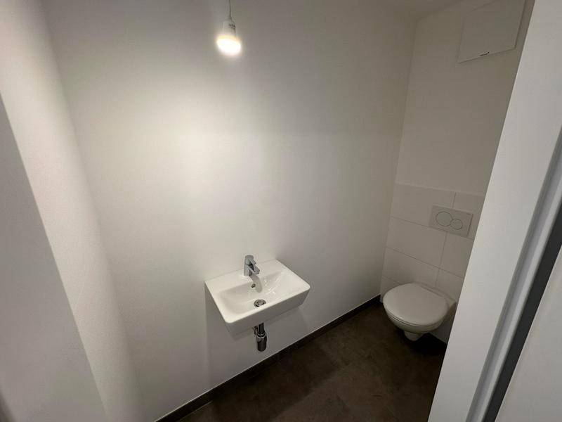 Modernes Gäste-WC mit wandhängendem Waschbecken und Toilette, in schlichtem Design.