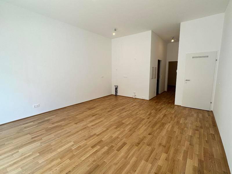 Geräumiger, heller Raum mit Holzboden und weiß gestrichenen Wänden, bereit zur Einrichtung.
