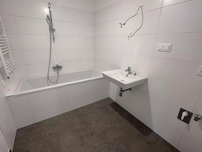 Modernes Badezimmer mit Badewanne, Waschbecken und weißen Fliesen, noch in Fertigstellung.