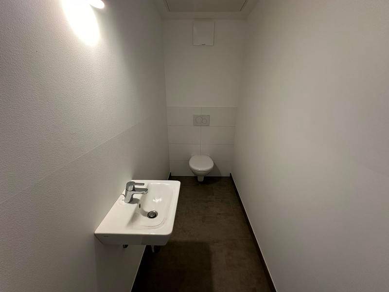 Helles Gäste-WC mit minimalistischem Design, wandhängendem Waschbecken und Toilette.